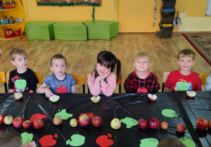 Dzieci siedzą przy stole z połówkami jabłek
